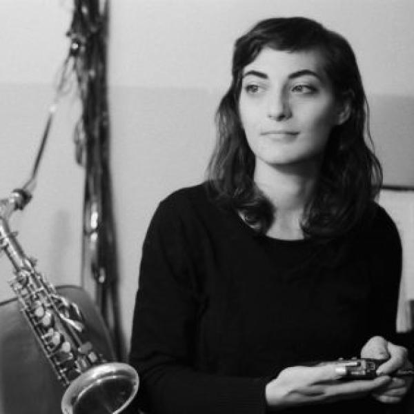 Lea Bertucci lounges on a chair with her saxophone behind her