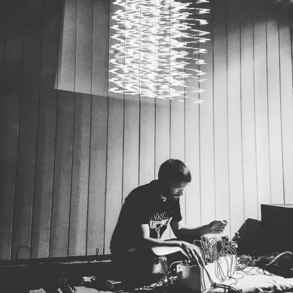 Felix playing modular synths in a black and white image, a wavey sculpture hangs in the room above him. 