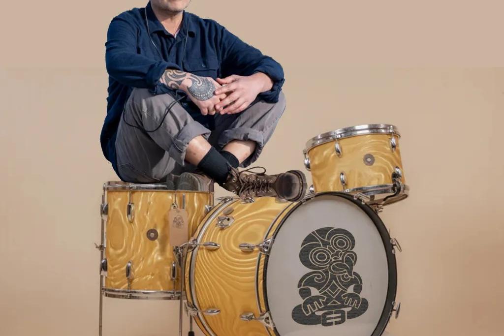 Riki Pirihi sits on a yellow drumkit with a blank background
