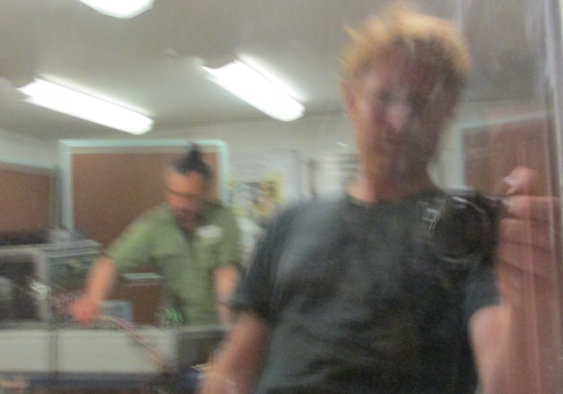 a blurry camera selfie featuring Dan Beban with a camera with Riki Gooch in the background