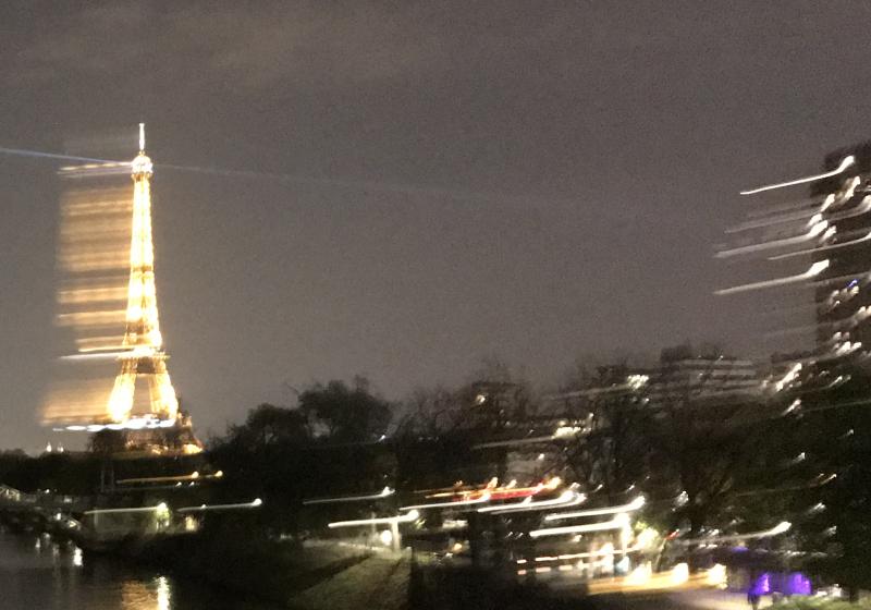 a highly blurred  photo of the Paris. The lights of the Eiffel Tower blurred with rapid movement of the camera.