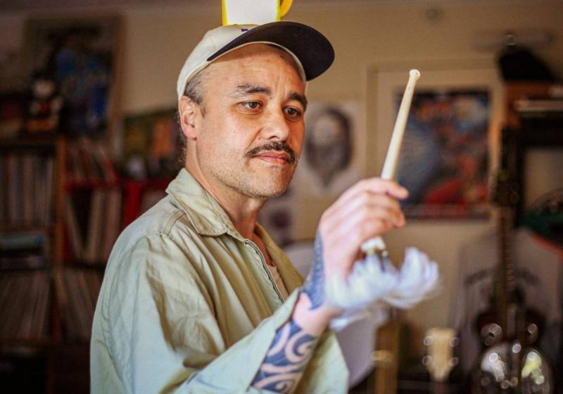 Riki using an albatross bone as a baton to conduct an unseen orchestra.