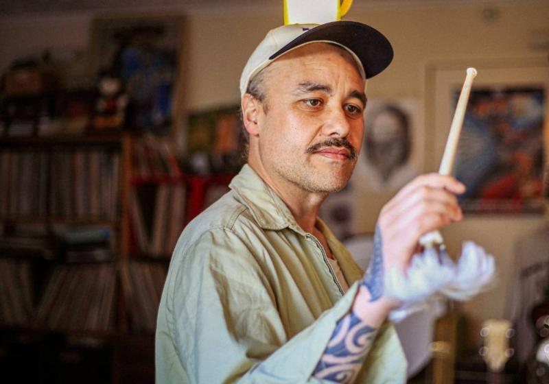 Riki using an albatross bone as a baton to conduct an unseen orchestra.