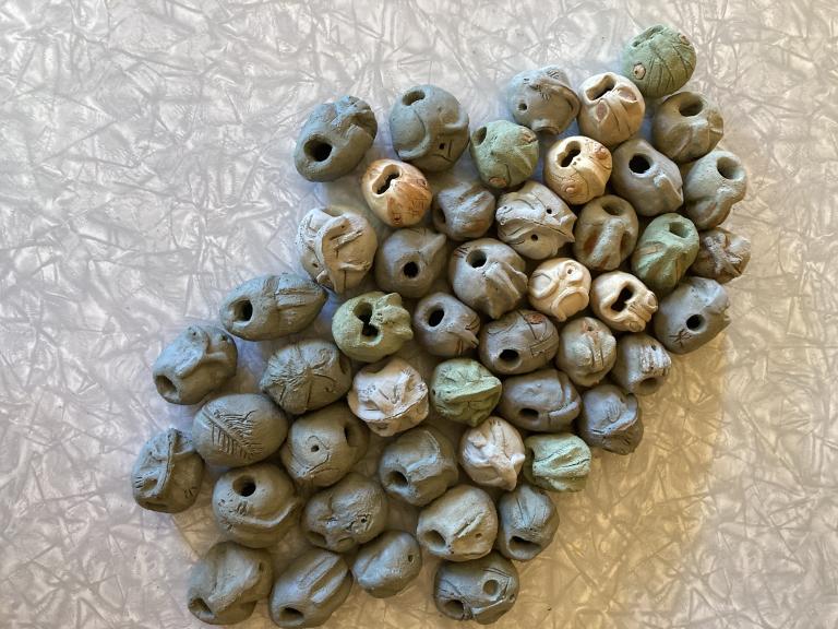A collection of round clay heads all with their mouths wide open singing silently