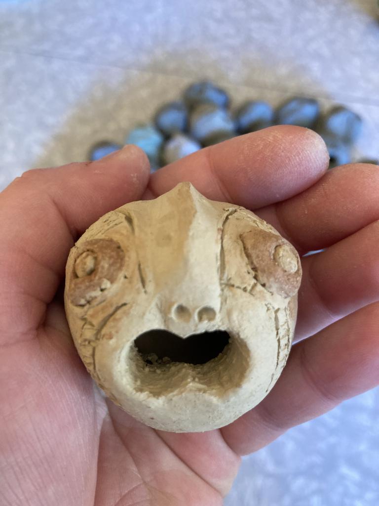 The clay head has protuding sad eyes. Their open mouth is hopeful