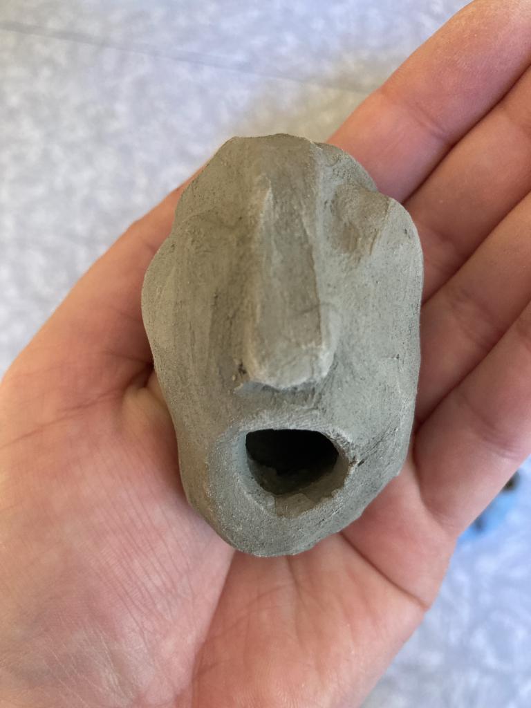 The slender clay head has along nose - their open mouth is humoured